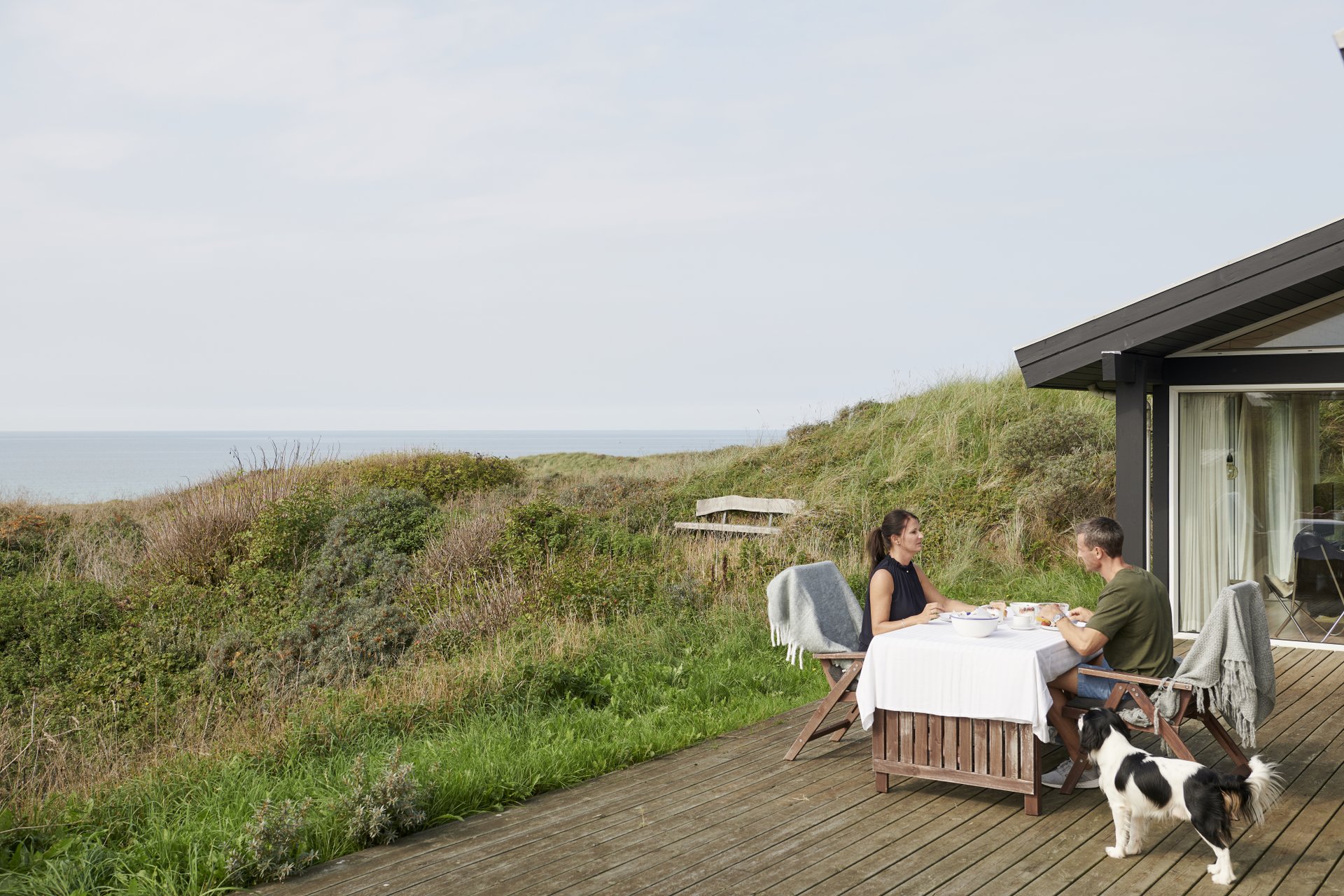 To personer spiser.morgenmad i et sommerhus ved stranden