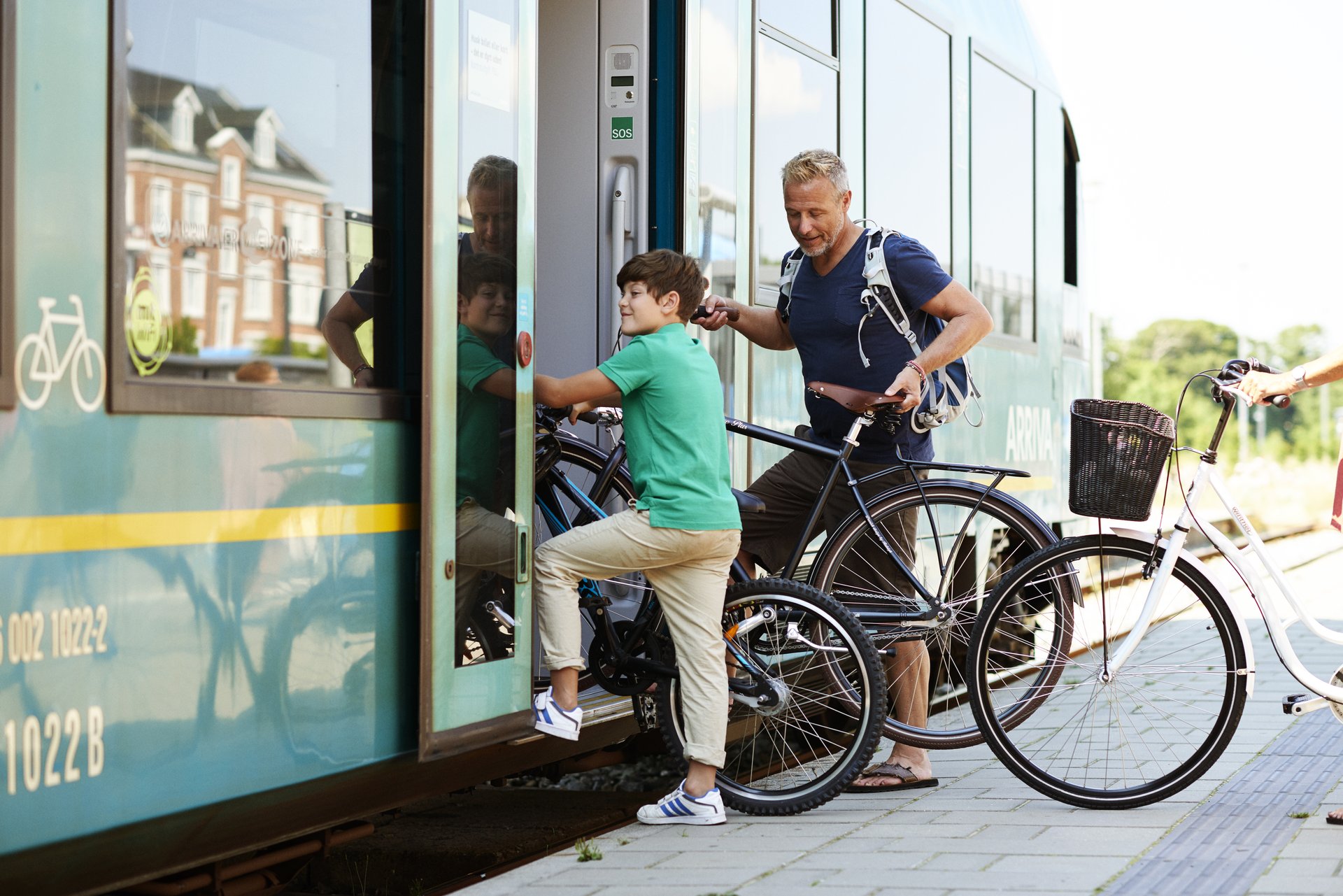 To personer stiger på toget med deres cykler