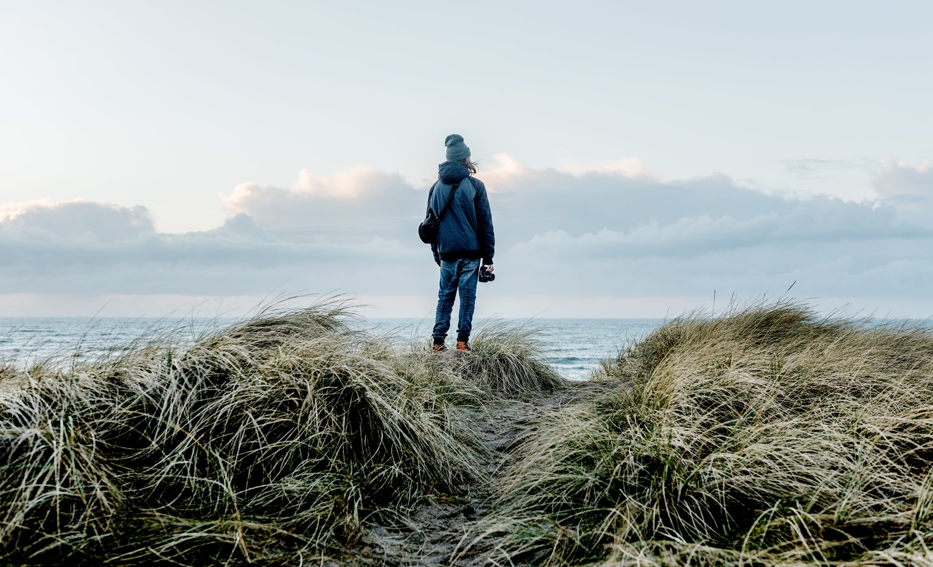 Foto af en person bagfra som nyder udsigten over havet ved Klitmøller