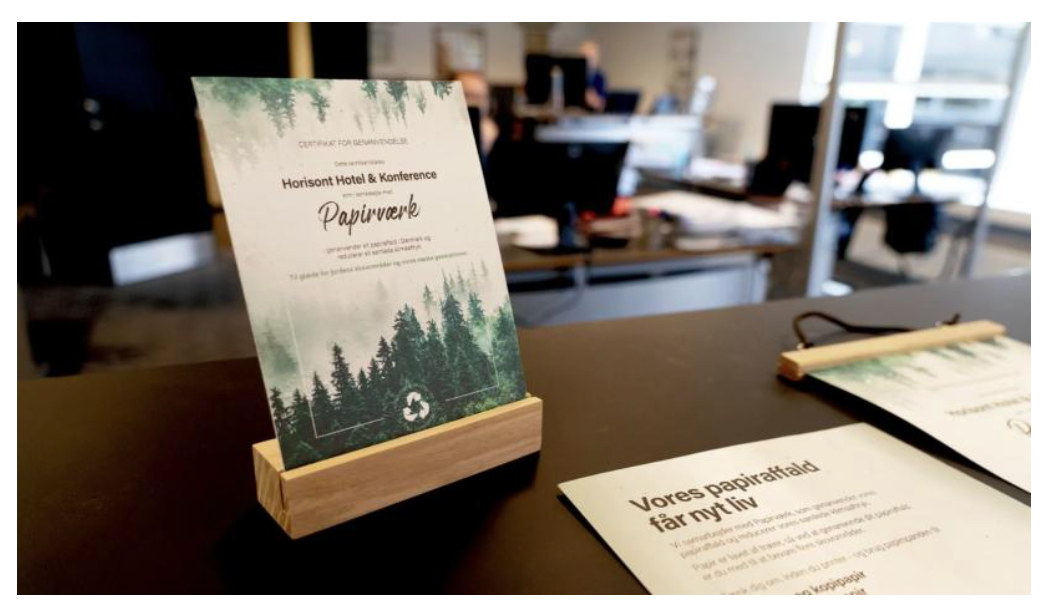 Foto af et skilt på en disk, der oplyser gæster om hotellets genanvendelse af restpapir