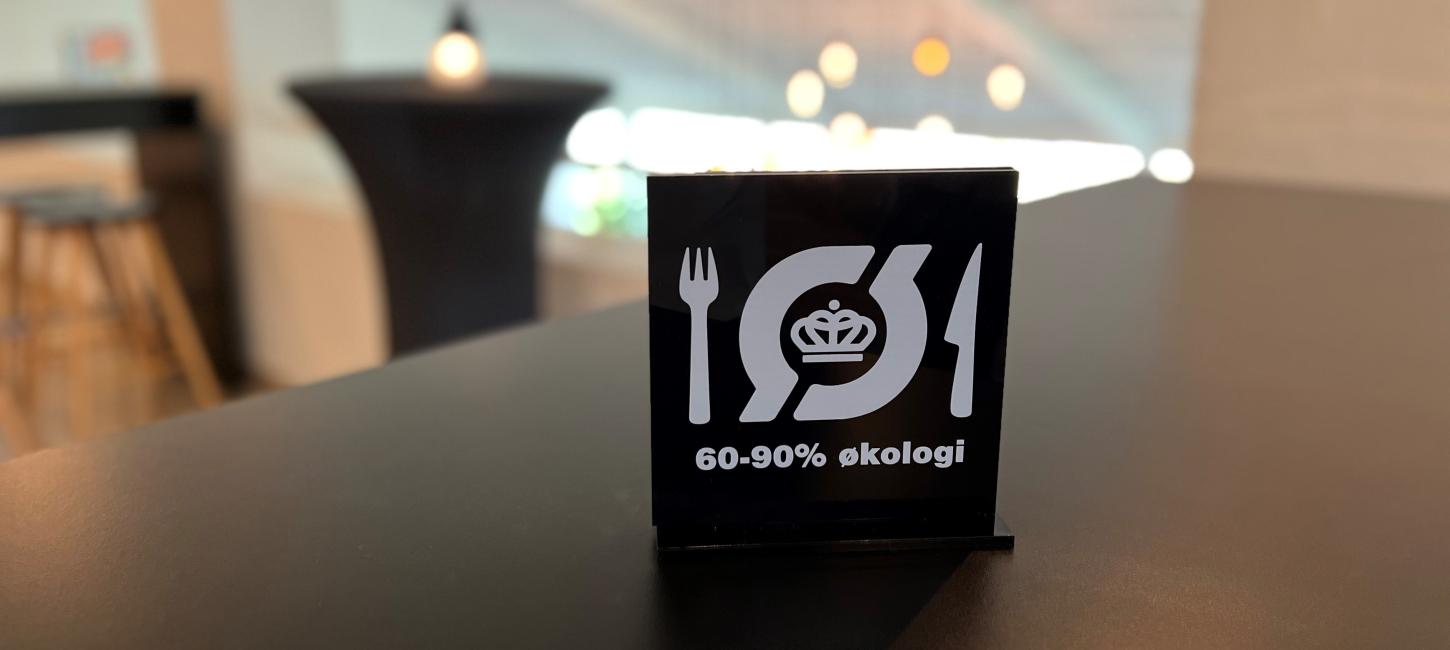 Et skilt med det økologiske spisemærke står på et bord