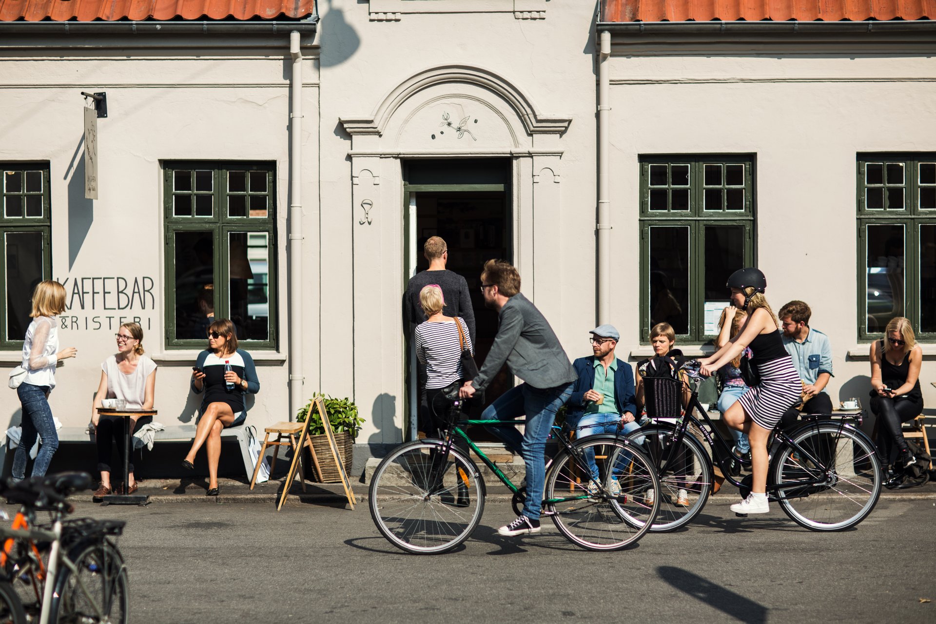 Folk sidder ved borde foran kaffebar