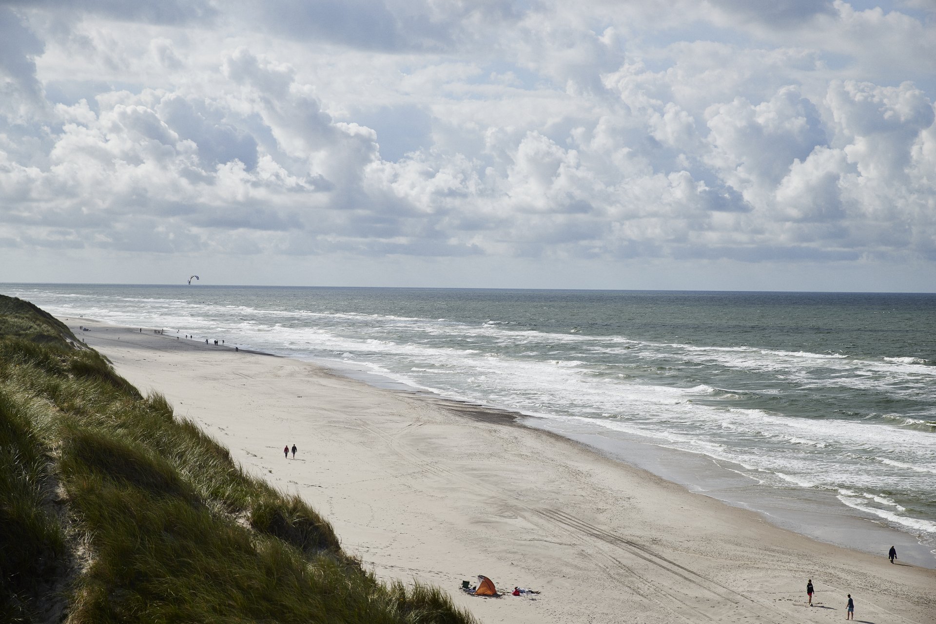 Kyst med mennesker gående på stranden
