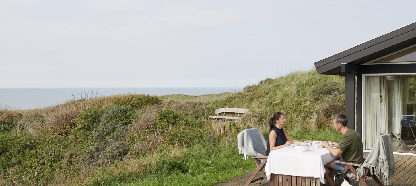 To personer spiser.morgenmad i et sommerhus ved stranden