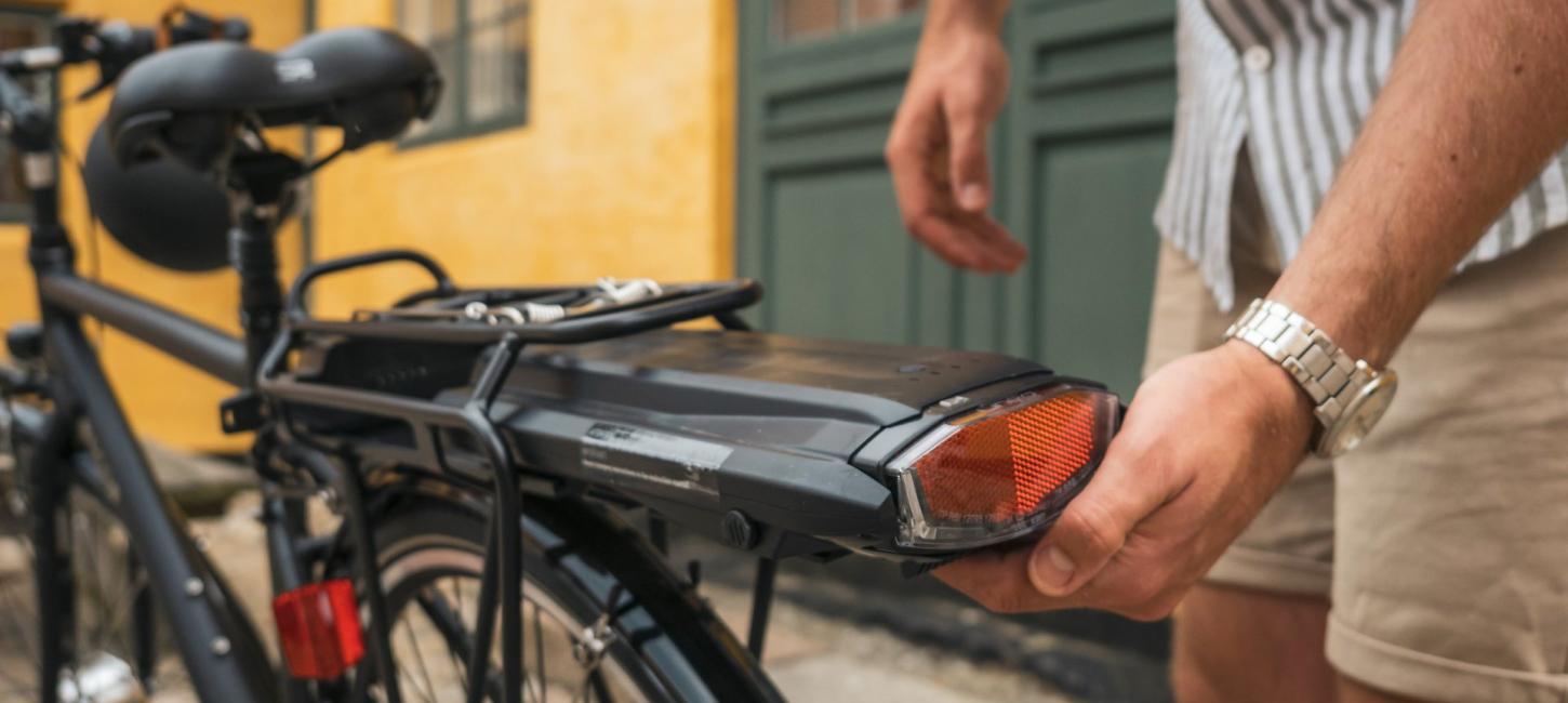 Person sætter elbatteriet på sin cykel