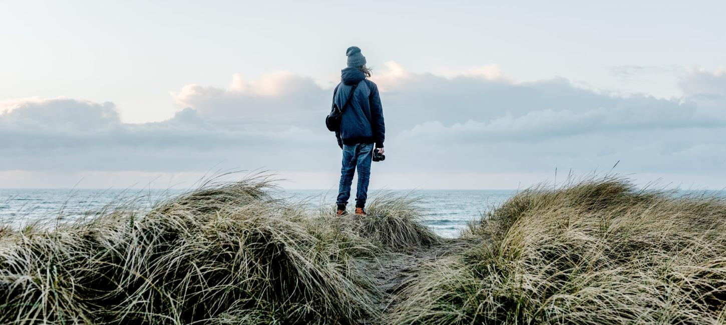 Foto af en person bagfra som nyder udsigten over havet ved Klitmøller