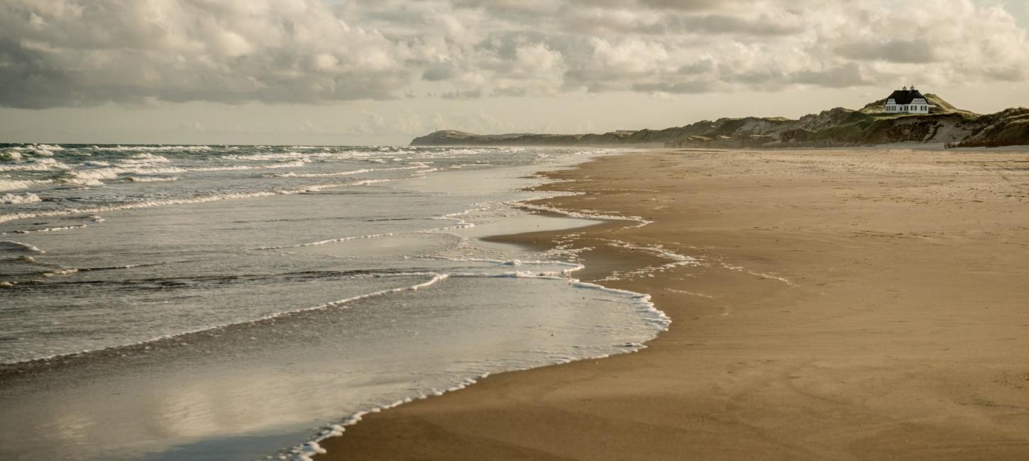 Foto af Løkken strand med en himmel fyldt med skyer