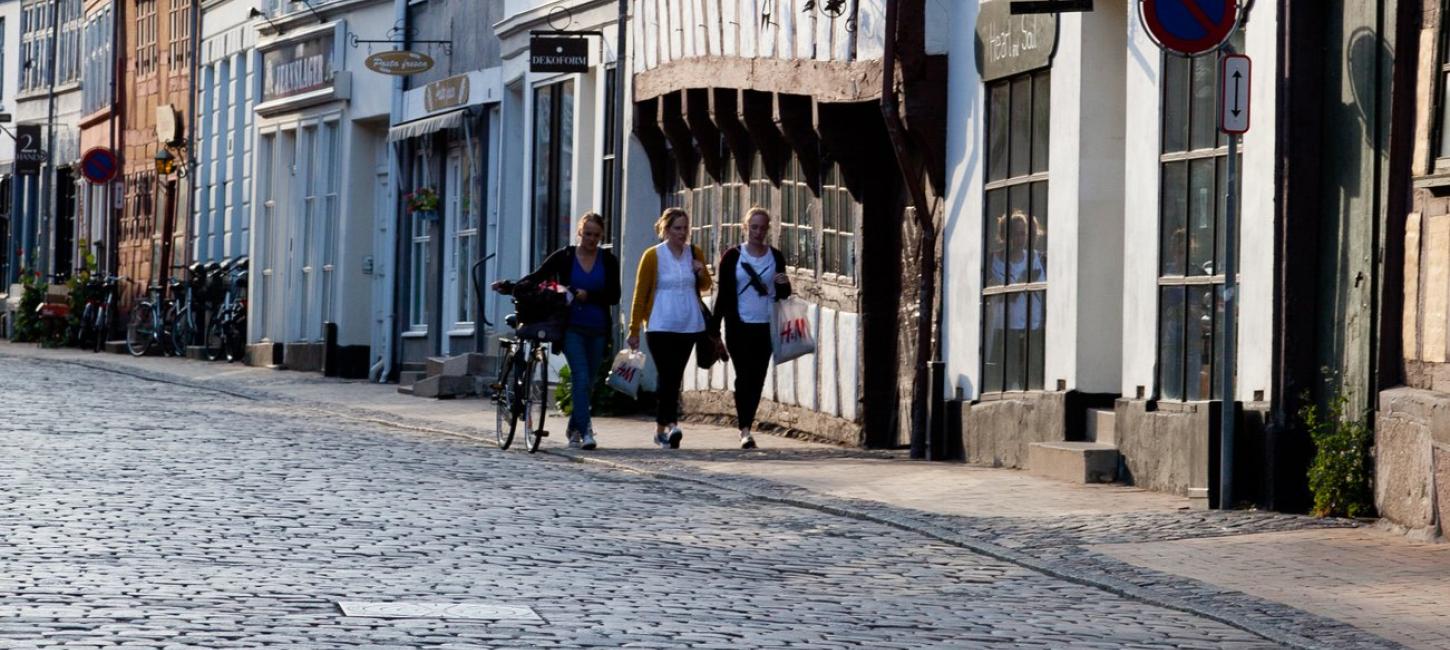 To personer trækker en cykel gennem Odenses små gader