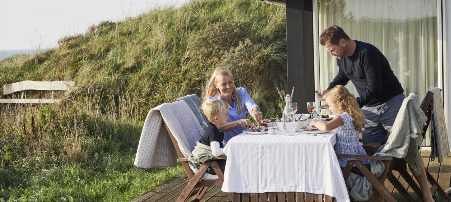 En familie sidder udenfor deres sommerhus
