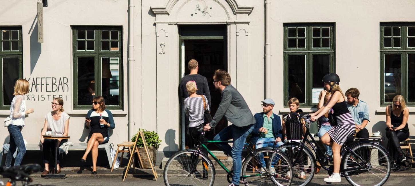 Folk sidder ved borde foran kaffebar