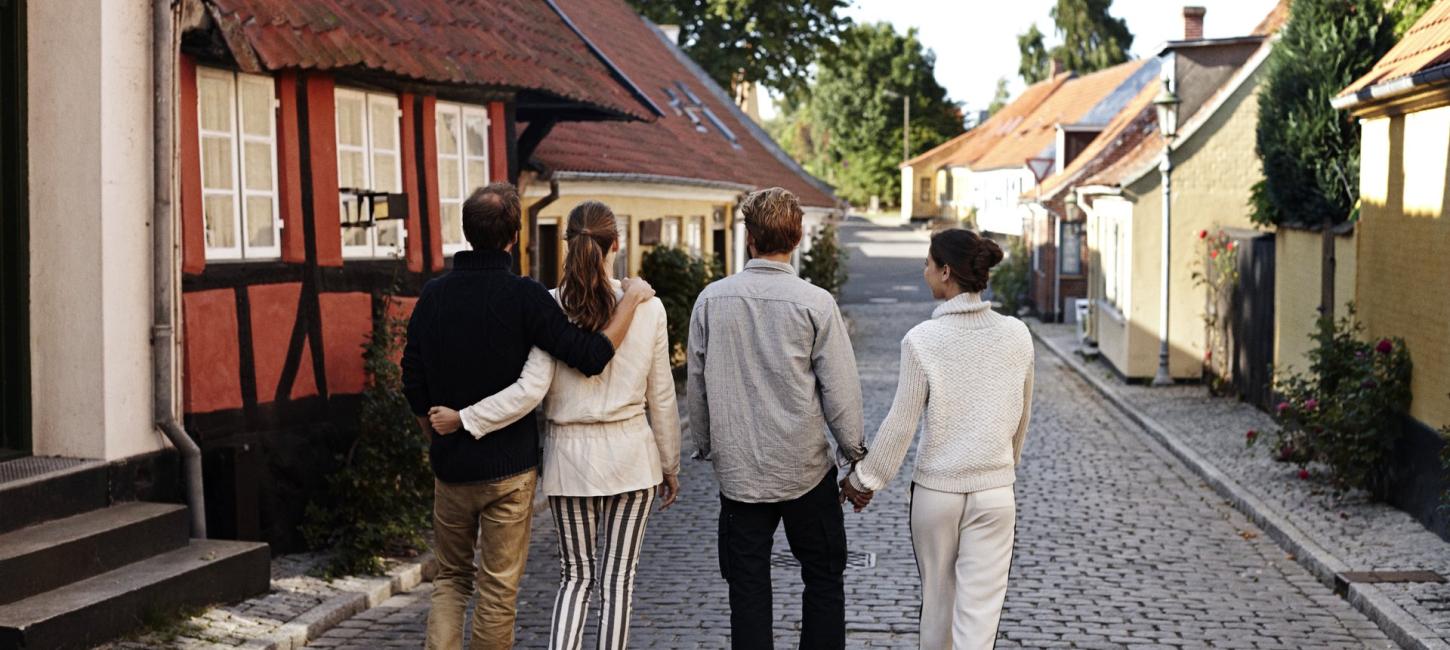 Fire mennesker går ned ad en brostensgade
