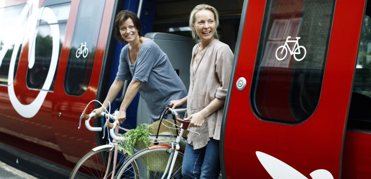 To personer stiger ud af toget med sine cykler